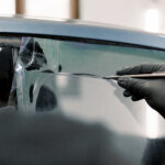 Cropped Image Of Hands Of Worker In Garage Tinting A Car Window
